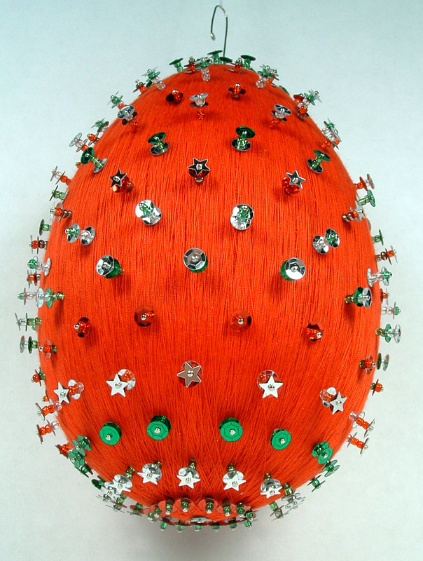 Bottom view of red thread wrapped ornament with sequins and pins.